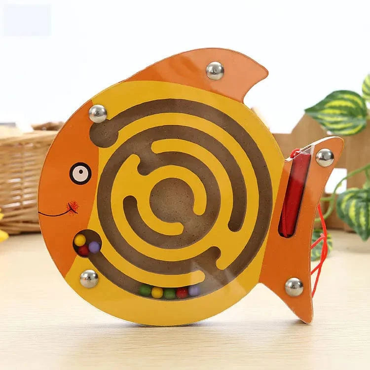 Fish-shaped maze toy with colorful balls on a light wooden surface