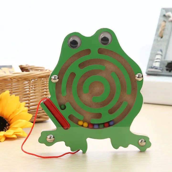 Green maze toy shaped like a frog with colorful balls on a light surface.