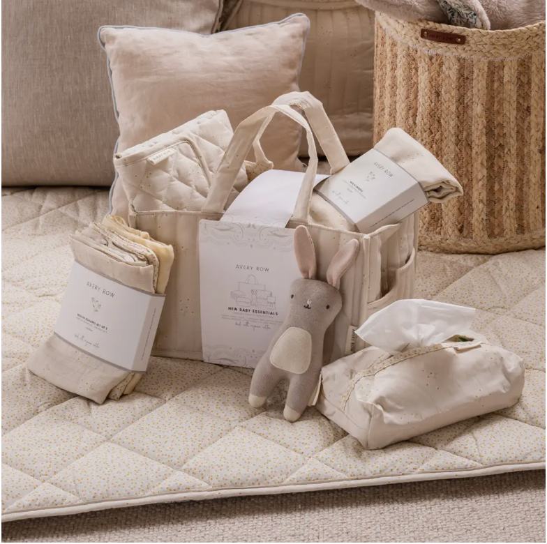 Baby care products including blankets, a toy, and a basket on a quilted surface.