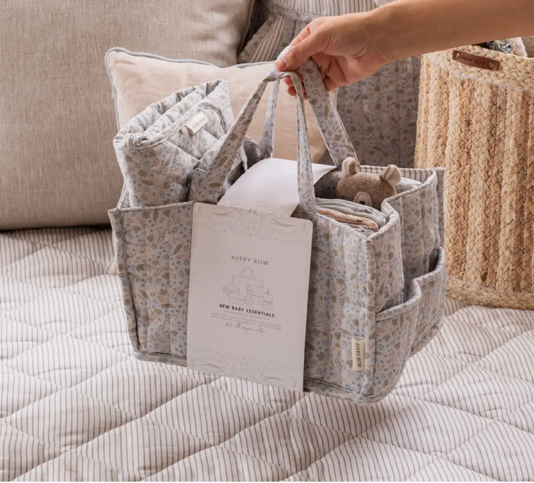 Baby essentials in a floral-patterned caddy on a bed
