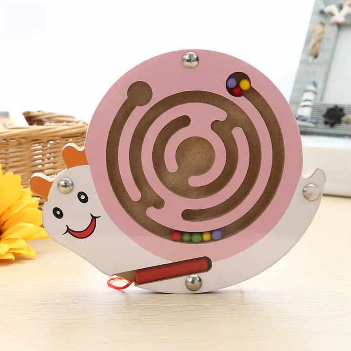 Pink maze toy shaped like a snail on a light wooden surface