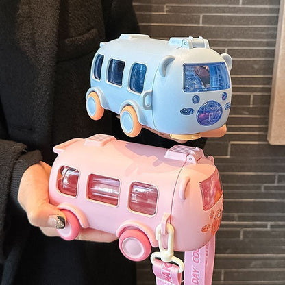 Two water bottle toy buses, one blue and one pink, held by a person against a brick wall.