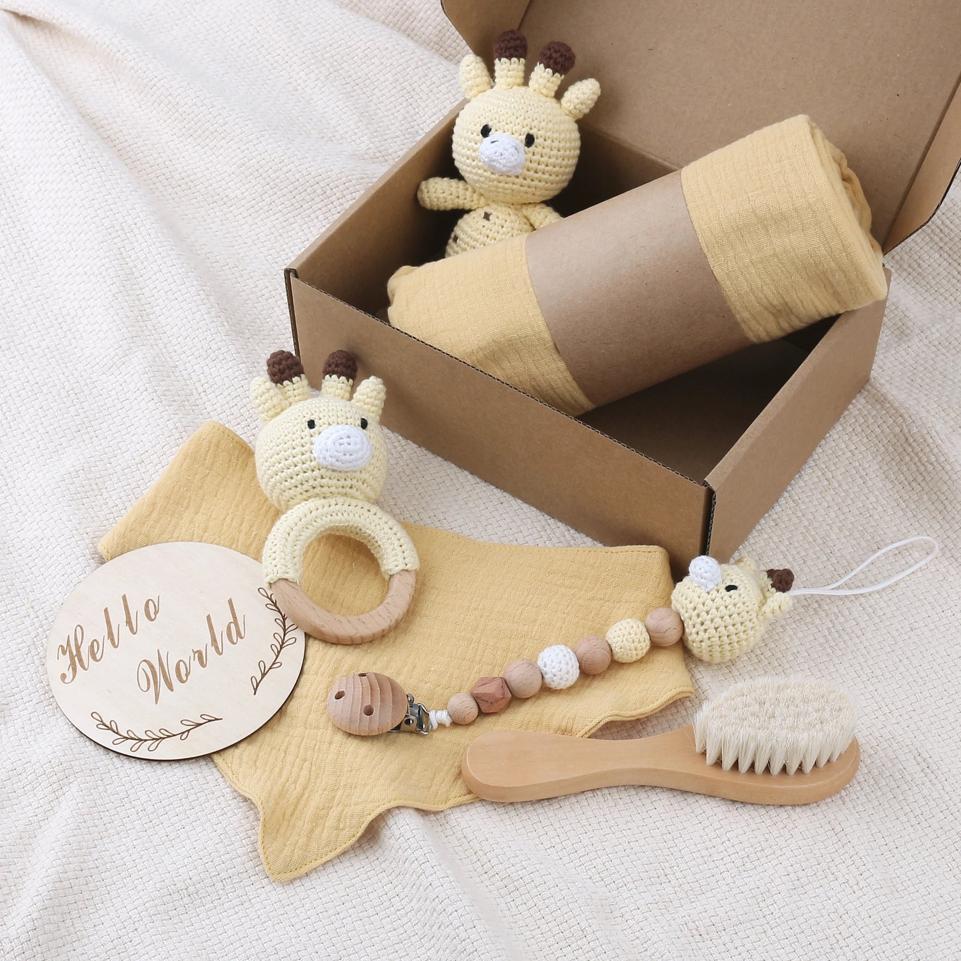 Baby care product set with toys, a brush, and a wooden tag on a soft surface.