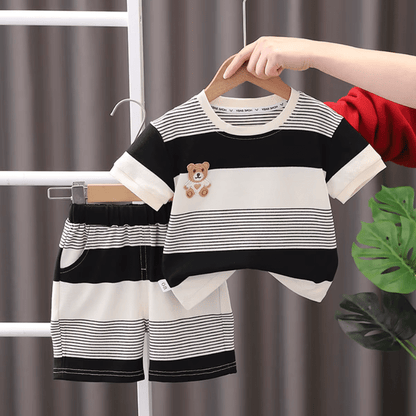 Children's black and white striped outfit with teddy bear design on a hanger against a neutral background.