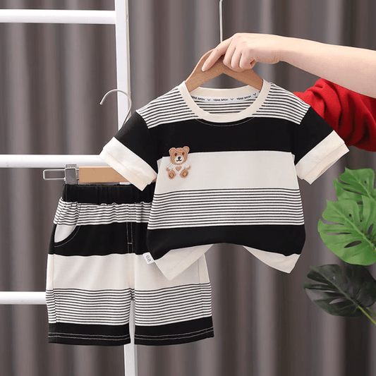 Children's black and white striped outfit with teddy bear design on a hanger against a neutral background.