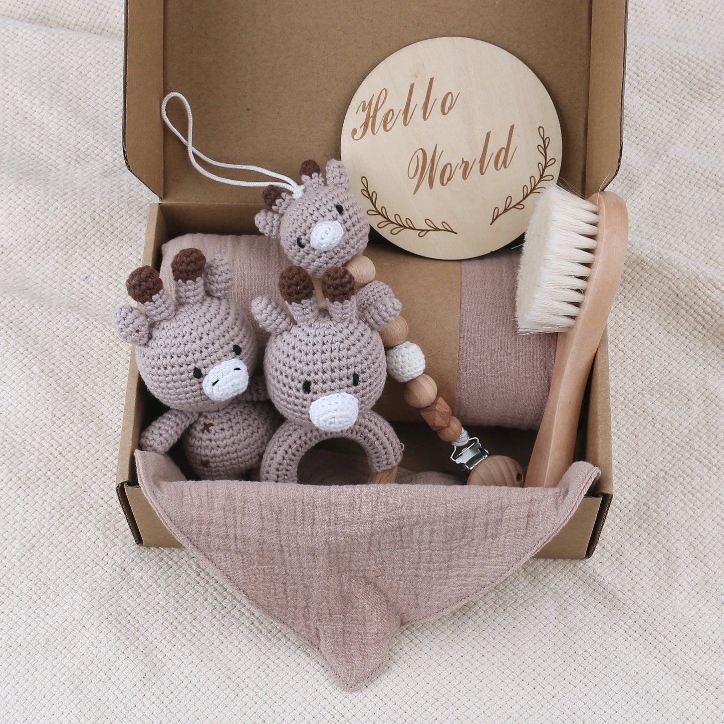Baby care set with crocheted animal, wooden rattle, and baby brush in a box labeled 'Hello World'.