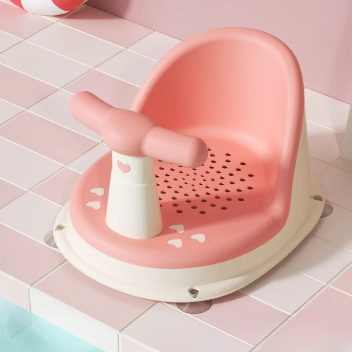 Pink bath seat with a white handle on a tiled bathroom floor