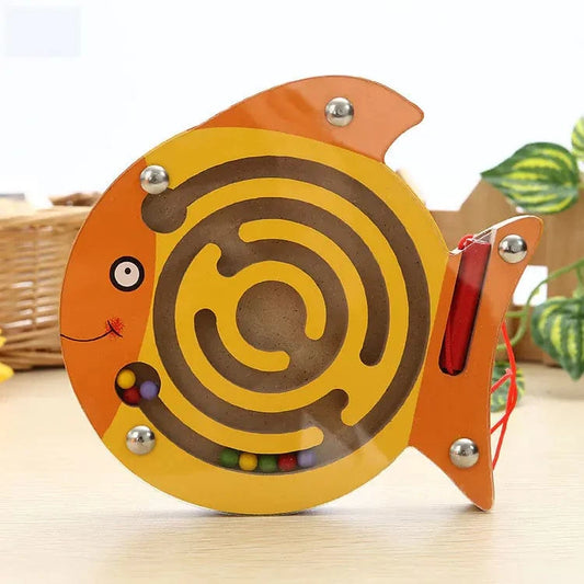 Fish-shaped maze toy with colorful balls on a light wooden surface