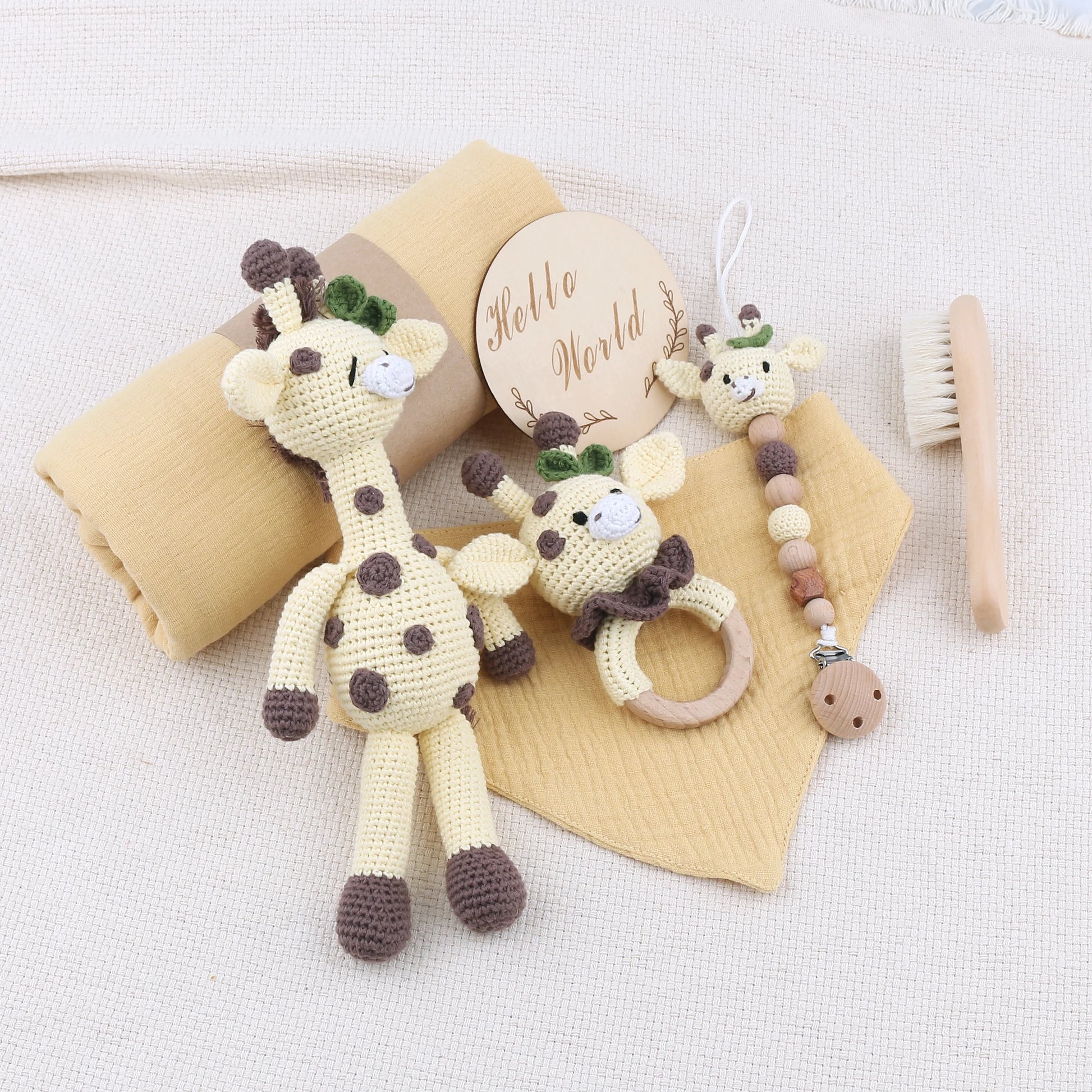 Set of baby toys including a crocheted giraffe, teething ring, and brush on a white background.