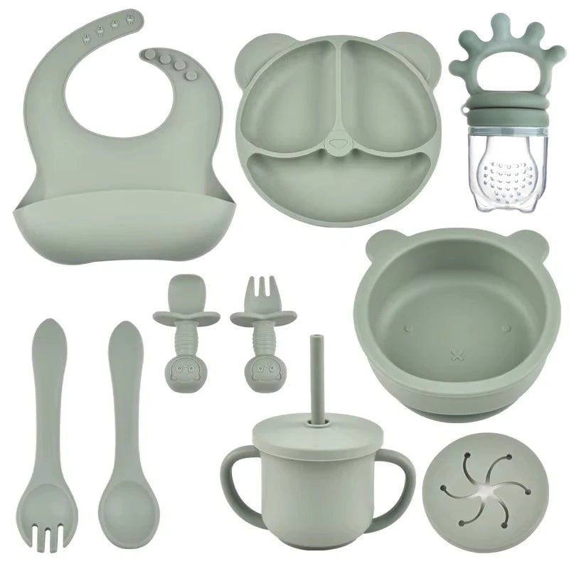 Collection of green silicone baby utensils and accessories on a white background