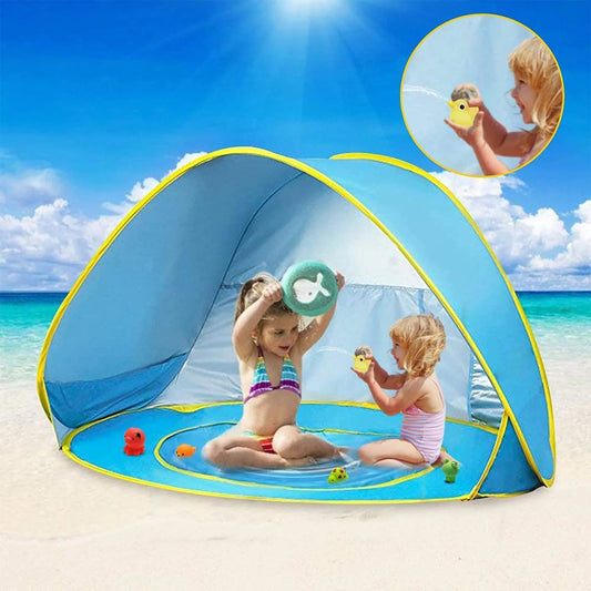 Children playing under a blue and yellow beach tent on a sunny day at the beach.