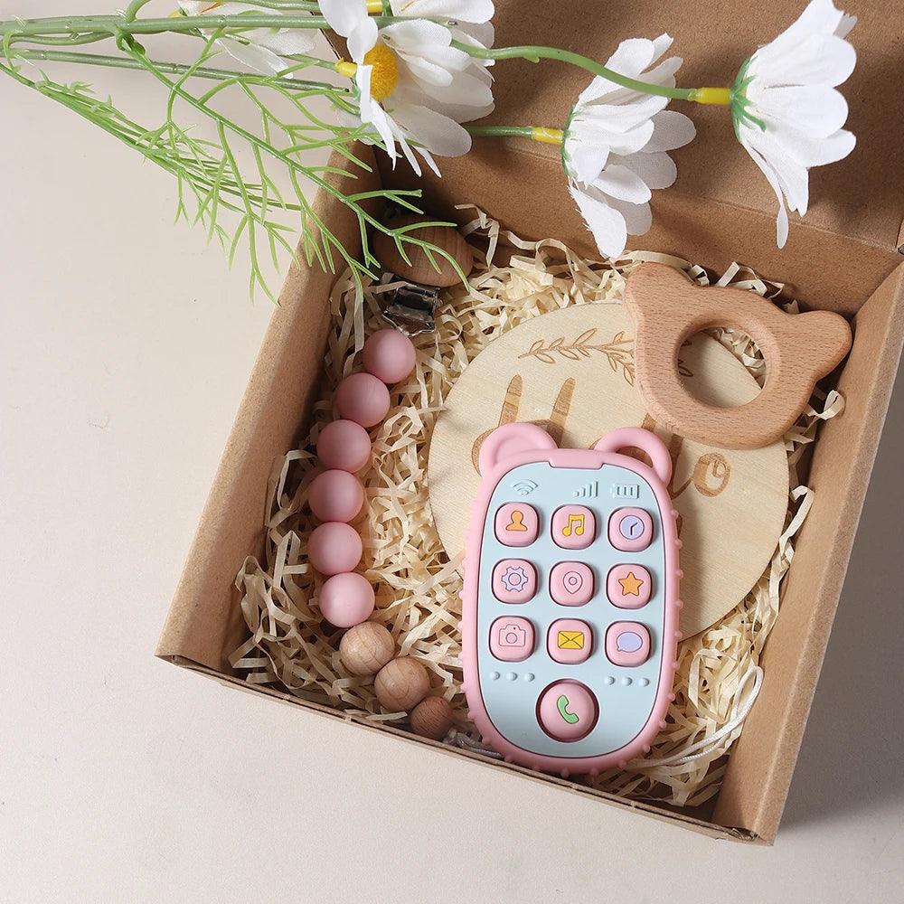Wooden baby teether, and a Pink teether with buttons in a box with flowers
