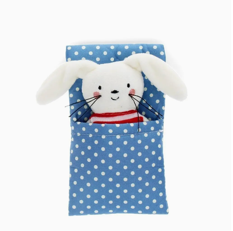 Plush rabbit toy peeking out from a blue polka dot bag on a white background