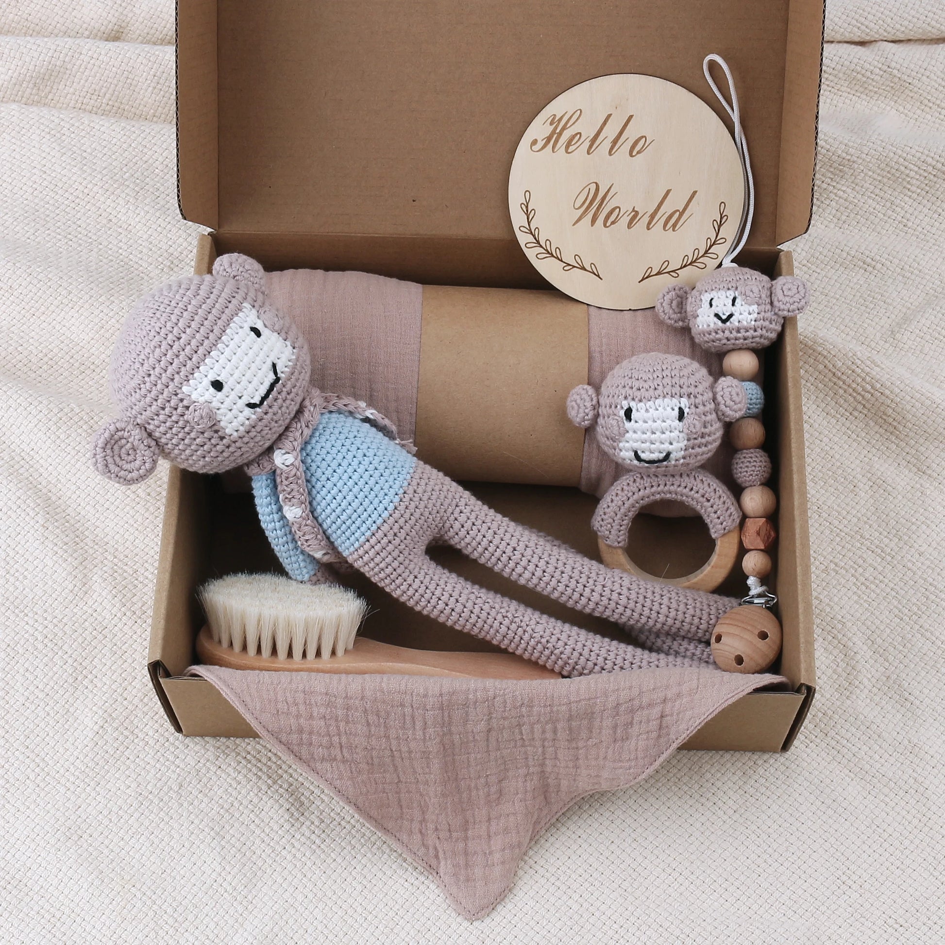 Baby toy set with crocheted monkey, brush, and teething ring in a box labeled 'Hello World'.