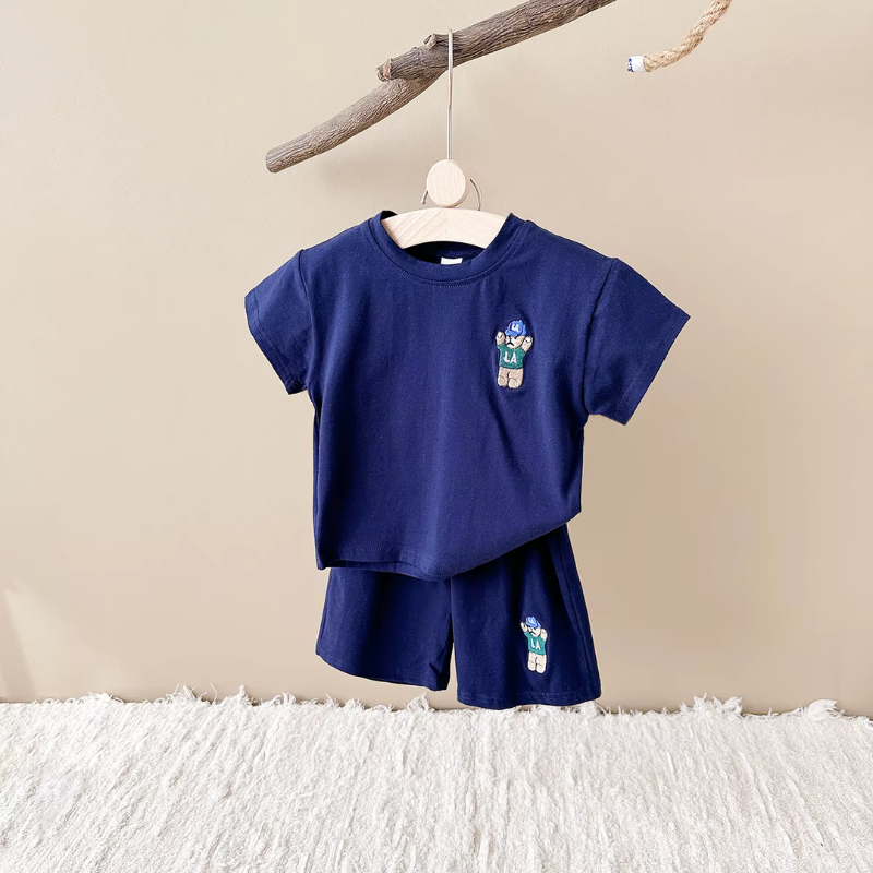 Navy blue SportBear children's outfit with cartoon character patches on a beige background