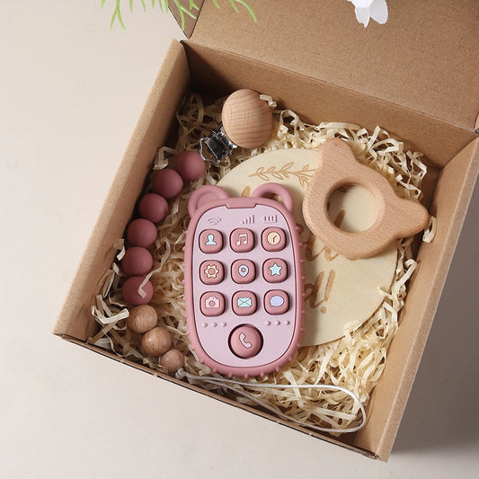 Pink Teether with phone buttons, wooden teething ring, and other toys in a box.