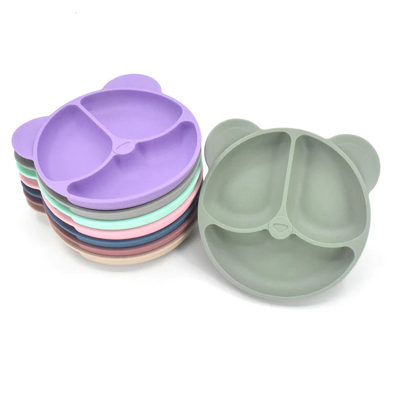 Stack of colorful silicone plates with divided sections on a white background