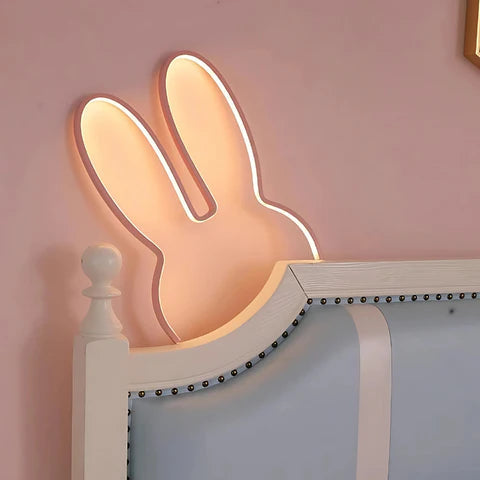 Decorative bunny-shaped light on a headboard against a pink wall