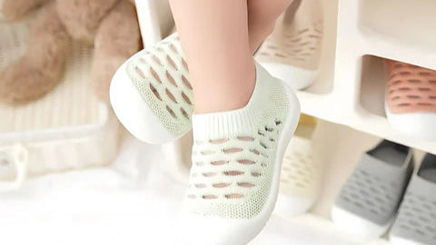 White mesh shoes worn by a child with a teddy bear in the background