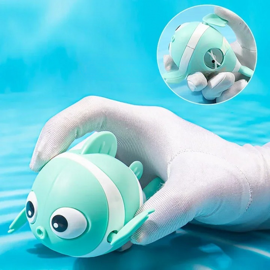 Green plush toy with white accents held by a gloved hand against a blue water background