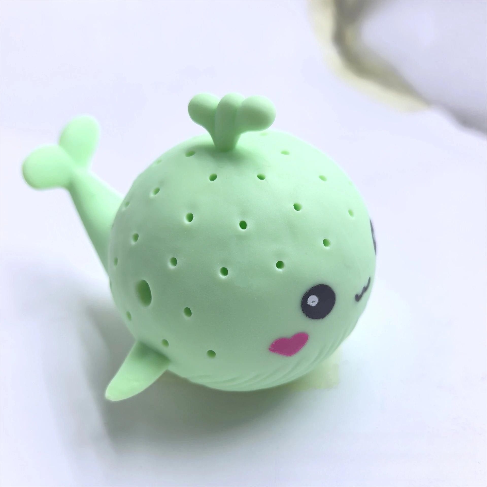 Green whale-shaped tea infuser on a white background