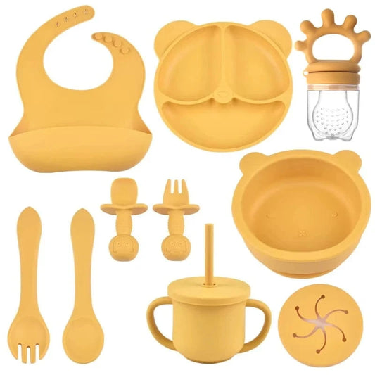 Collection of yellow silicone baby utensils and accessories on a white background