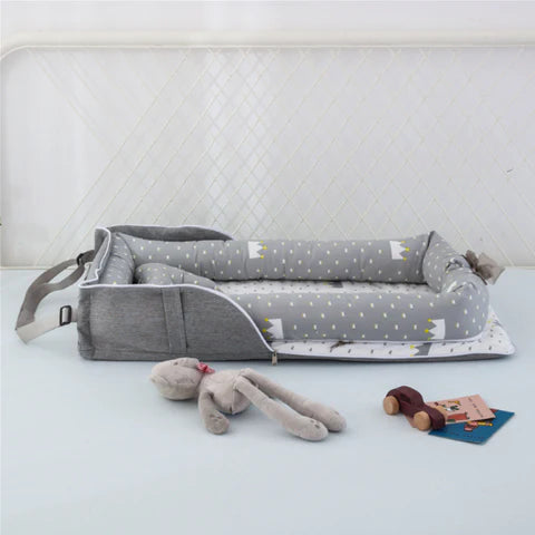 Gray baby crib with star pattern and toys on a white surface