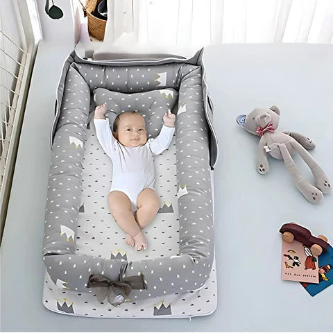 Baby lying in a gray and white patterned crib with toys around