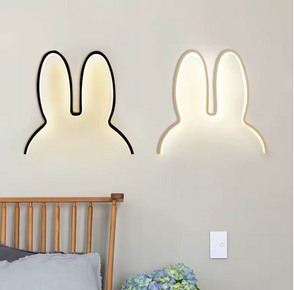 Two rabbit-shaped wall lights on a gray wall above a bed.