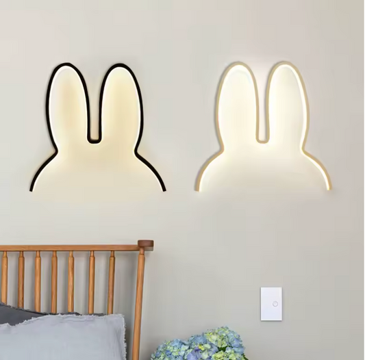 Two rabbit-shaped wall lights on a gray wall above a bed.